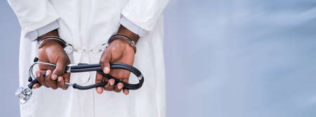 Close-up Of Doctor Hands With Stethoscope In Handcuffs