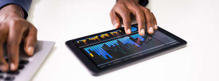 Close-up Of A Businessman's Hand Analyzing Graph On Digital Laptop At Workplace