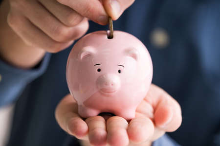 Financial Advisor Inserting Coin In Piggybank.401K Planの写真素材