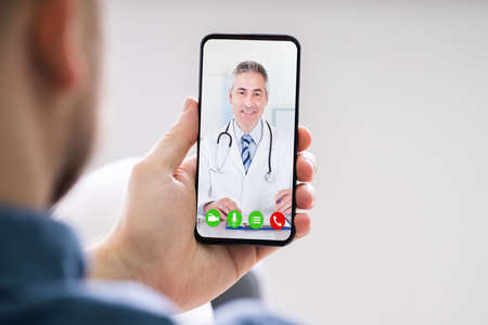 Person Videochatting With Doctor On Mobile Phoneの写真素材
