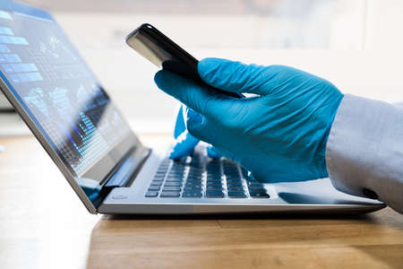 Man In Gloves Protecting From Coronavirus Typing On Computer On Quarantine At Homeの写真素材