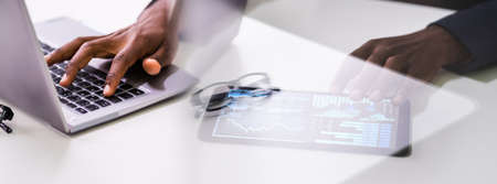 Close-up Of A Businessman's Hand Analyzing Graph On Digital Laptop At Workplaceの写真素材