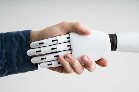 Close-up Of Businessperson Shaking Hands With Robotの写真素材