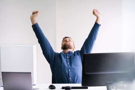 Close-up Of A Young Businessman Stretching His Arms At Workplaceの写真素材