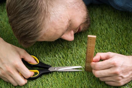 Close-up Of A Man Cutting Green Grass Measured With Rulerの写真素材