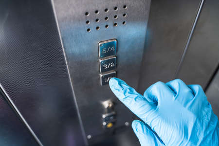 Man Using Gloves To Press Button To Protect From Coronavirus Infectionの写真素材