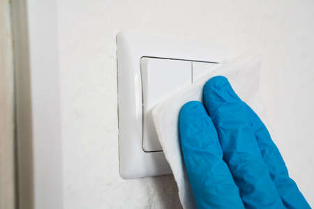 Man Wiping Light Switch With Sanitizer Against Virus Infection
