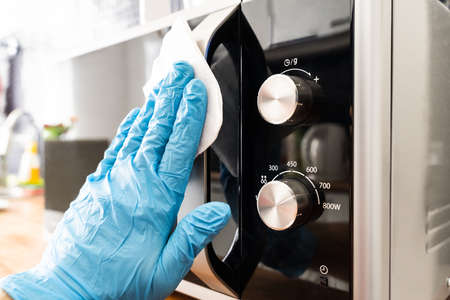 Man Wiping Microwave Oven Handle With Sanitizer Against Virus Infectionの写真素材