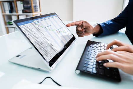 Two Young Businesspeople Analyzing Gantt Chart On Laptop
