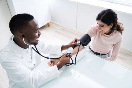 Close-up Of Doctor Measuring Patients Blood Pressure With Stethoscopeの写真素材