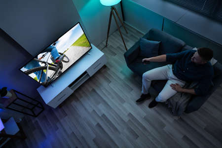 Man Lying On Sofa Watching Television At Home