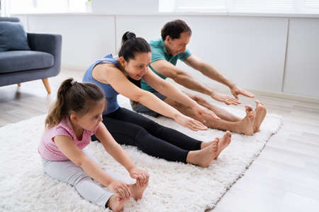 Family Doing Stretching Yoga Exercise At Homeの写真素材