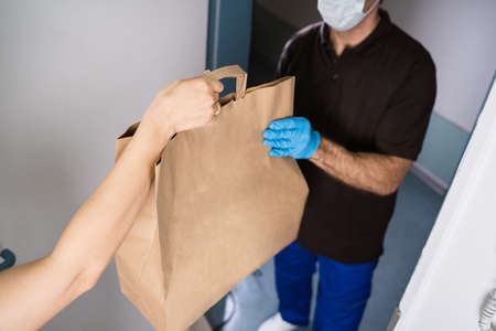 Courier Delivering Food And Meal To Woman At Home From Restaurantの写真素材