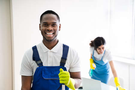 Portrait Of A Happy Male Janitor With Cleaning Equipment In Officeの写真素材