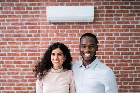 Portrait Of Happy Couple Holding Remote Control Air Conditionerの写真素材