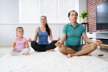 Family Practicing Yoga Meditation Happy At Homeの写真素材