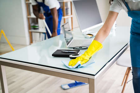 Young Male And Female Cleaners Cleaning Officeの写真素材
