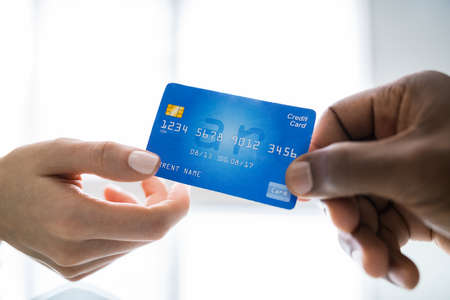Close-up Of Two Businesspeople Hands Holding Credit Card