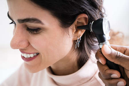 Close-up Of Female Doctor Examining Patient's Ear With Otoscopeの写真素材