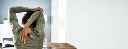 Employee Stretching At Office Desk At Workの写真素材