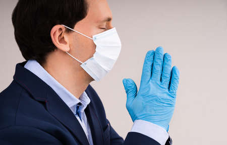 Man In Gloves And Face Mask Praying During Coronavirus Pandemicの写真素材