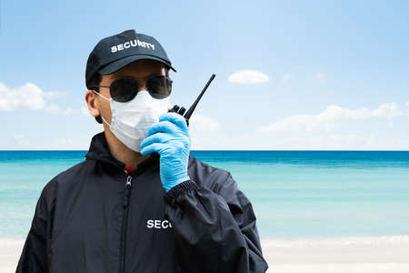 Security Guard Standing In Face Mask At The Beach