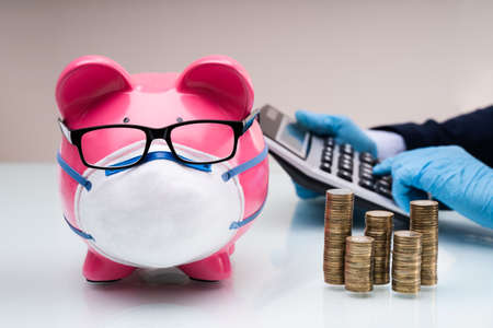 Piggybank With Face Mask During Coronavirus Pandemic Near Accountantの写真素材