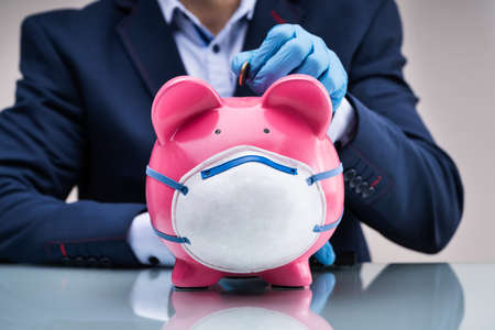 Inserting Coin In Piggybank To Save Money During Coronavirus Crisisの写真素材