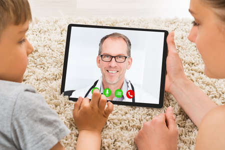 Woman With Kid In Online Video Conference Call With Doctorの写真素材