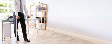 Patient Person With Crutches In Office. Workplace Disabilityの写真素材