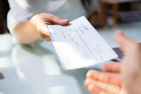 Hand Giving Payroll Compensation Paycheck. Salary Chequeの写真素材
