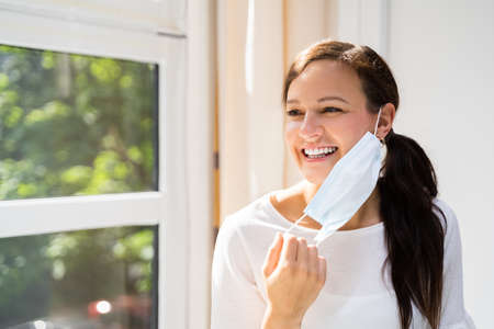Woman Removing Face Mask To Breath Freely