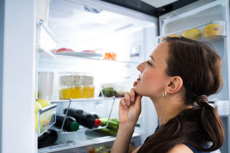 Hungry Woman Looking For Food In Kitchen At Homeの写真素材