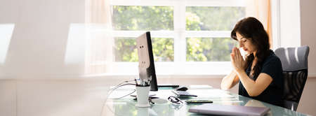 Employee Woman Praying Near Computer At Officeの写真素材