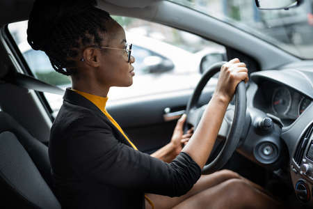African Woman Holding Steering Wheel While Driving Carの写真素材