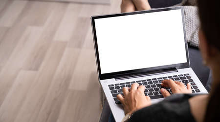 Woman With Laptop Computer At Home With Blank Display