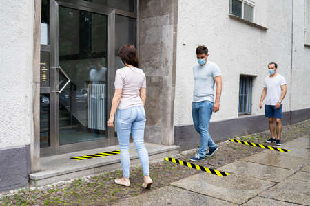 People Line With Social Distancing Protocol And Medical Face Masks