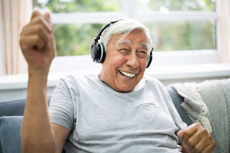 Smiling Older Senior Listening Music On Headphonesの写真素材