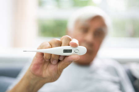 Ill Sick Senior Man Showing Temperature In Winter