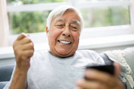 Smiling Older Senior Listening Music On Mobile Phone