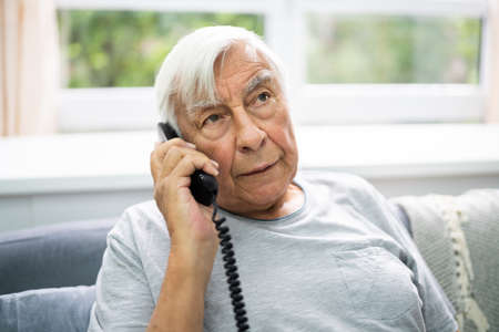 Senior Old Man Talking On Landline Telephoneの写真素材