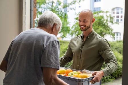 Grocery Food Shopping Help For Elder Senior Standing At Doorの写真素材