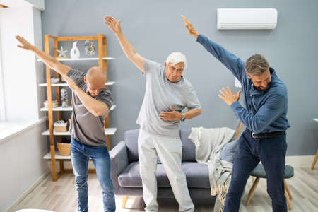 Three Generation Men Dancing And Exercising With Senior Grandpa