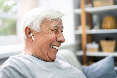 Smiling Older Senior Listening Music On Mobile Phoneの写真素材