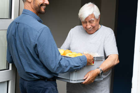 Grocery Food Shopping Help For Elder Senior Standing At Doorの写真素材