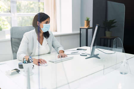 Employee In Office Social Distancing Using Sneeze Guard And Face Maskの写真素材