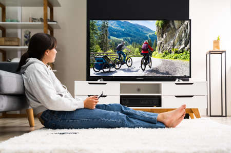 Lady Watching Television. Woman Near Couch Holding Tablet