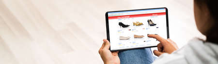 Woman Internet Shopping Using Tablet On Couch