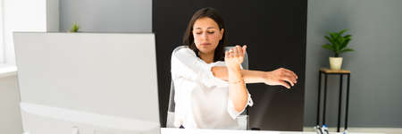 Woman Stretches At Office Desk. Stretch Exercise On Chairの写真素材