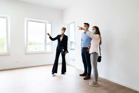 Happy Couple Buying New Home With Realtor Wearing Face Masksの写真素材